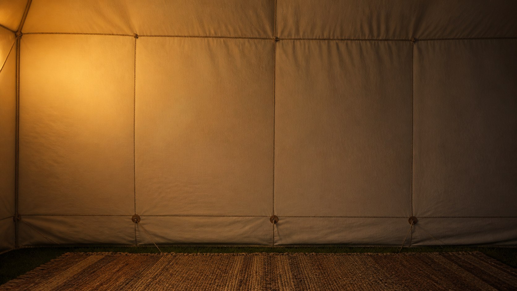 A cream canvas wall lit by one lantern