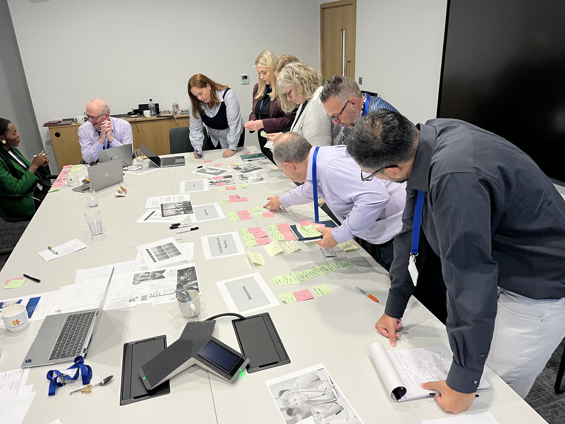 Stakeholders around a table mapping the end-to-end applicant journey with printed journey maps and sticky notes