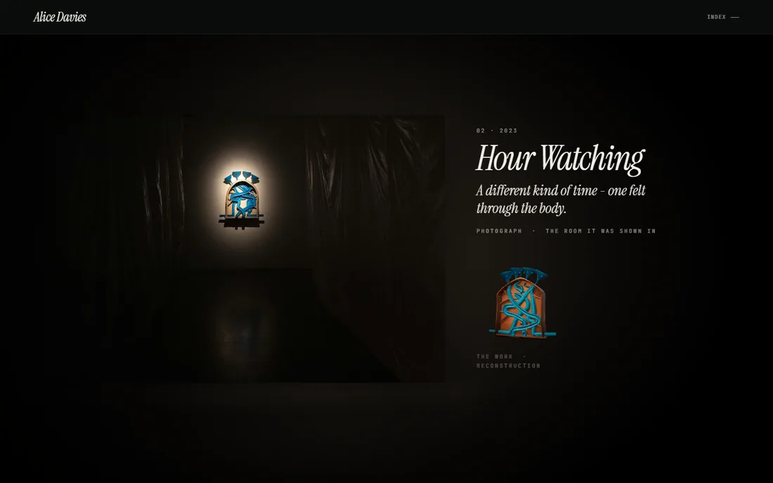 Her photograph of a lit arched wall piece at the end of a corridor of hanging plastic sheet, over a wet floor, with a small reconstruction beside the caption