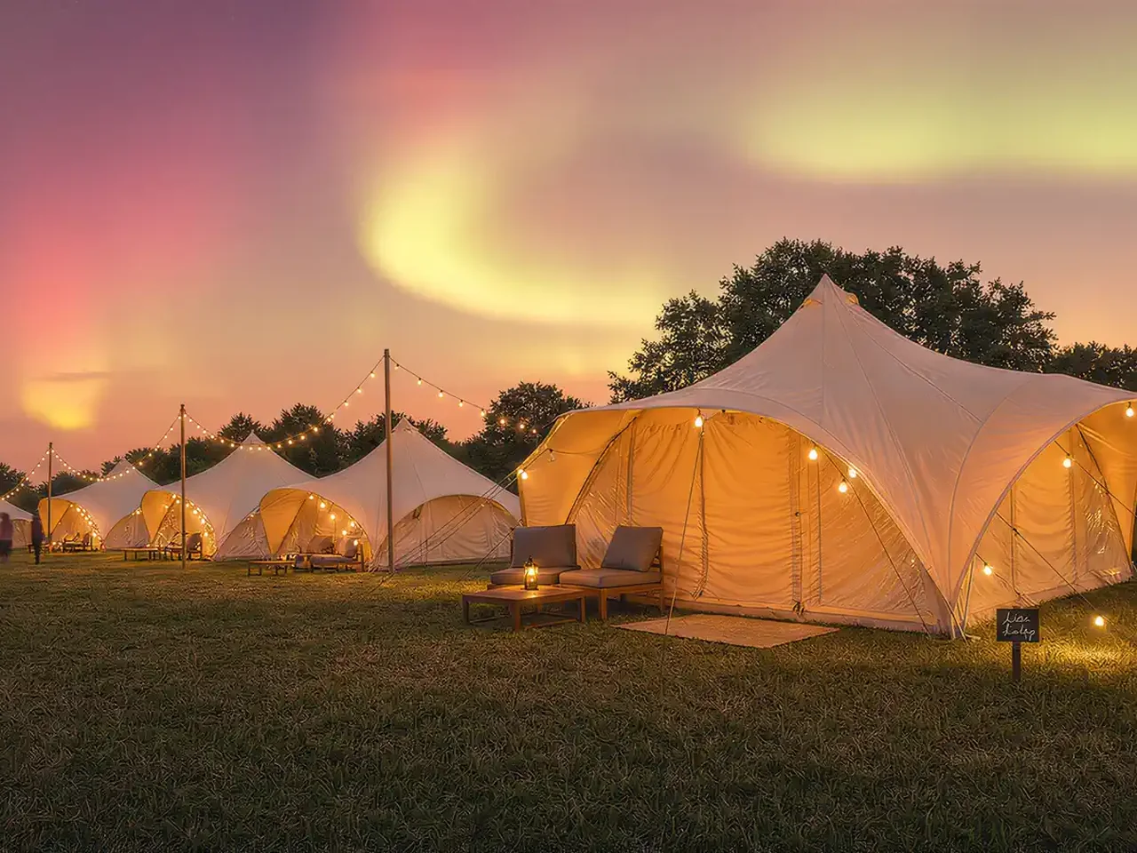 A magenta and coral dusk sky over a field of cream tents