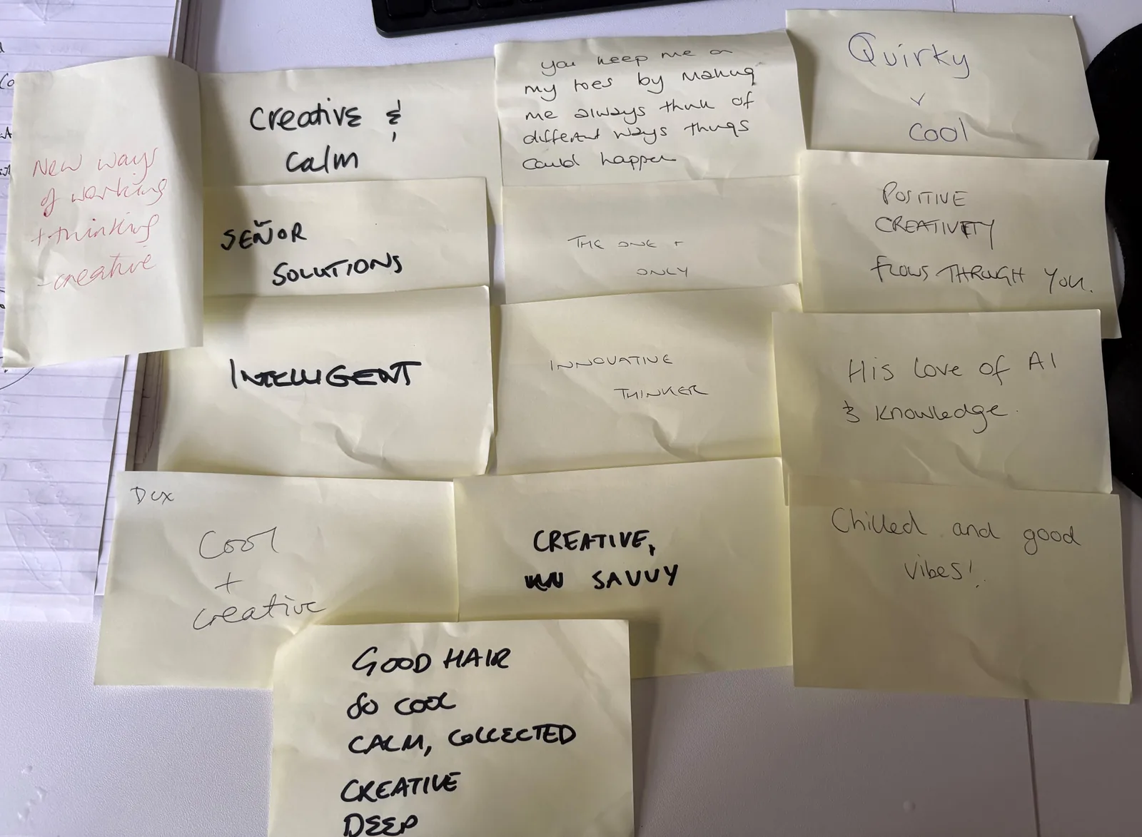 A photograph of fourteen handwritten sticky notes laid out on a desk. Among them: you keep me on my toes by making me always think of different ways things could happen; new ways of working and thinking creative; positive creativity flows through you; his love of AI and knowledge; innovative thinker; creative and calm; and good hair