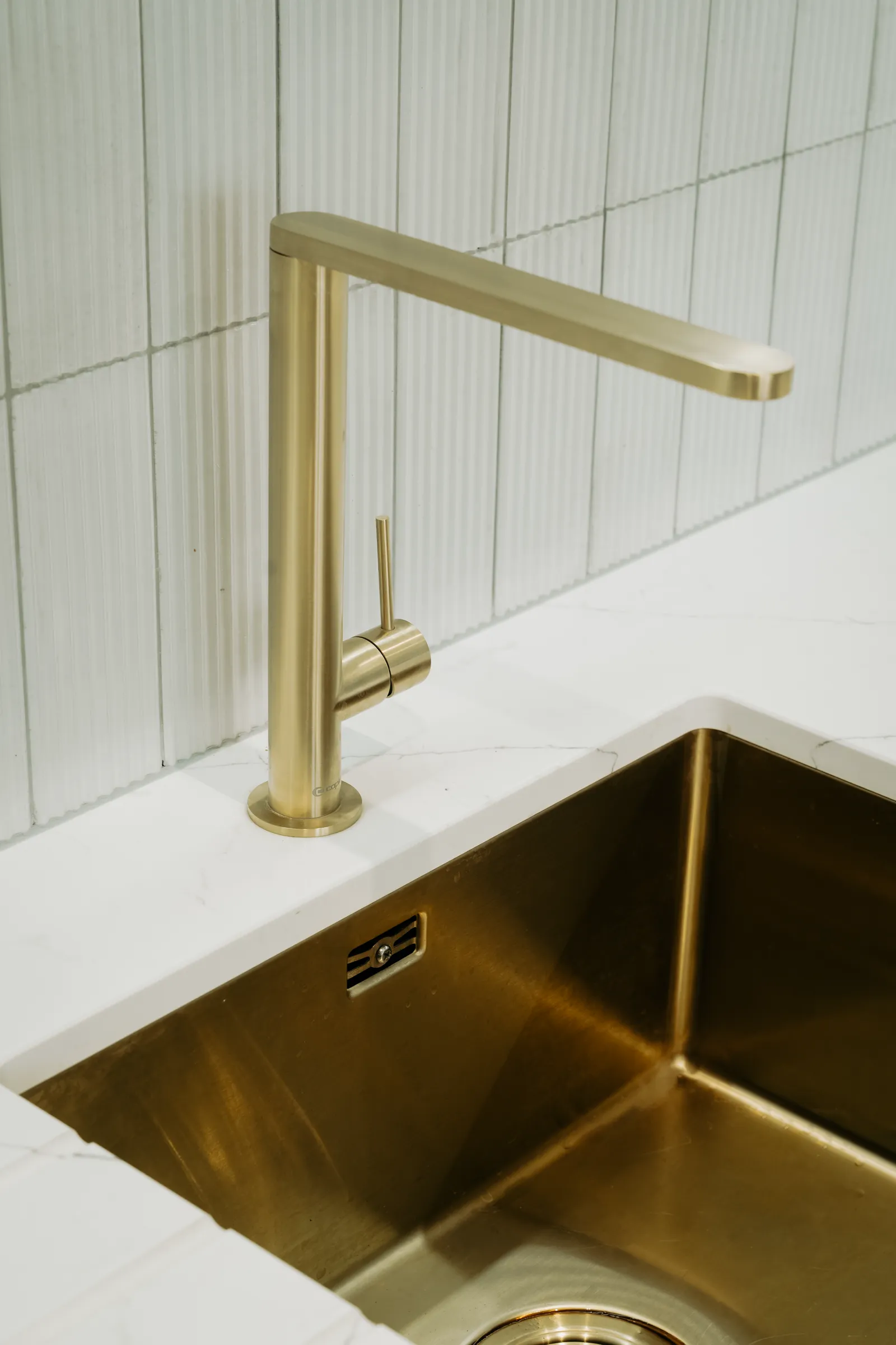 Brushed brass tap over an undermounted brass sink