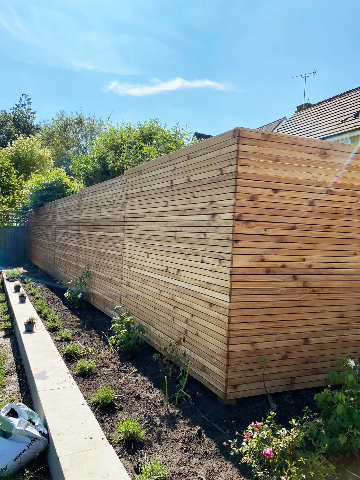 Horizontal cedar-clad garden screen with planting bed