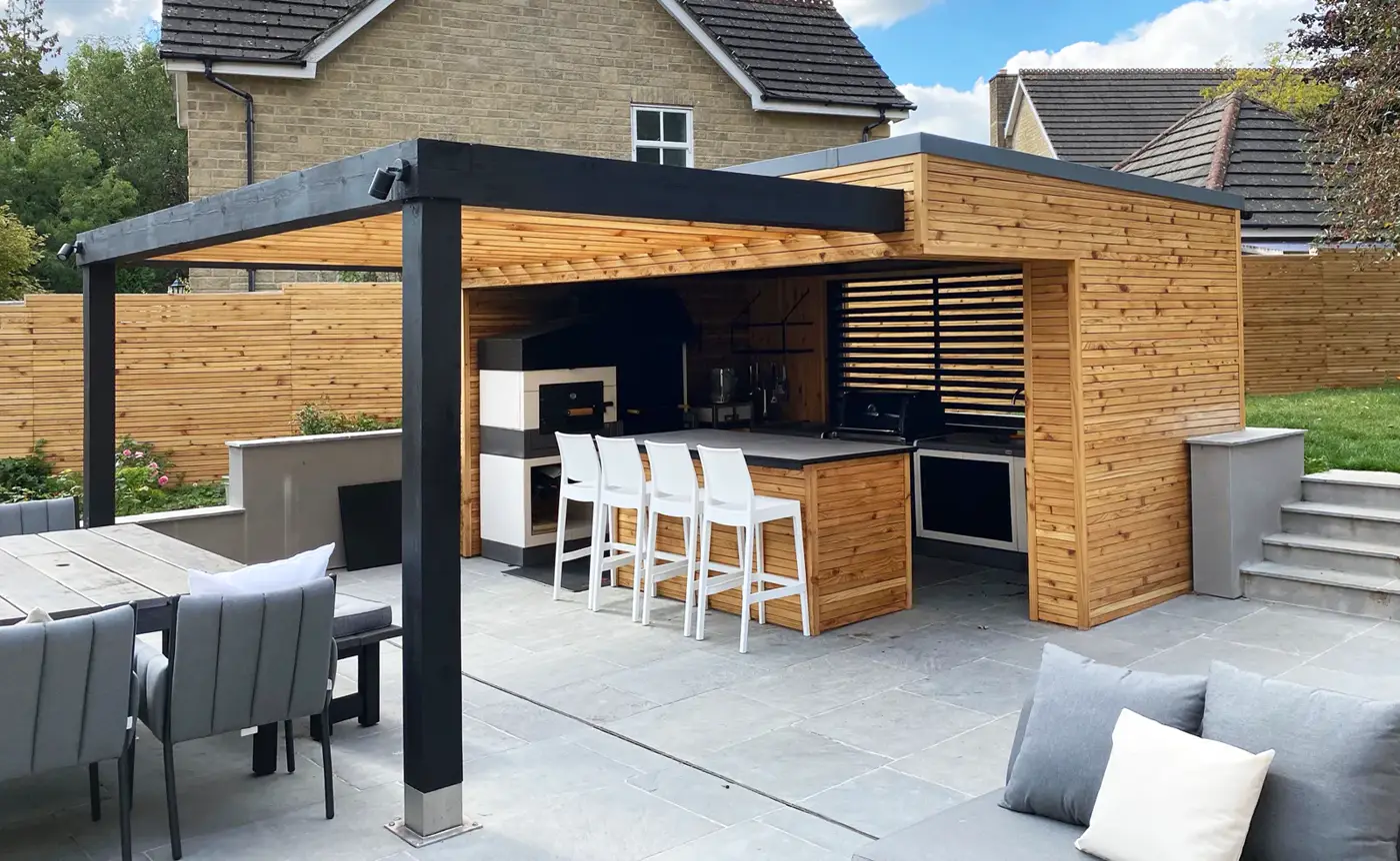 Outdoor kitchen with black steel pergola frame, timber cladding and bar seating
