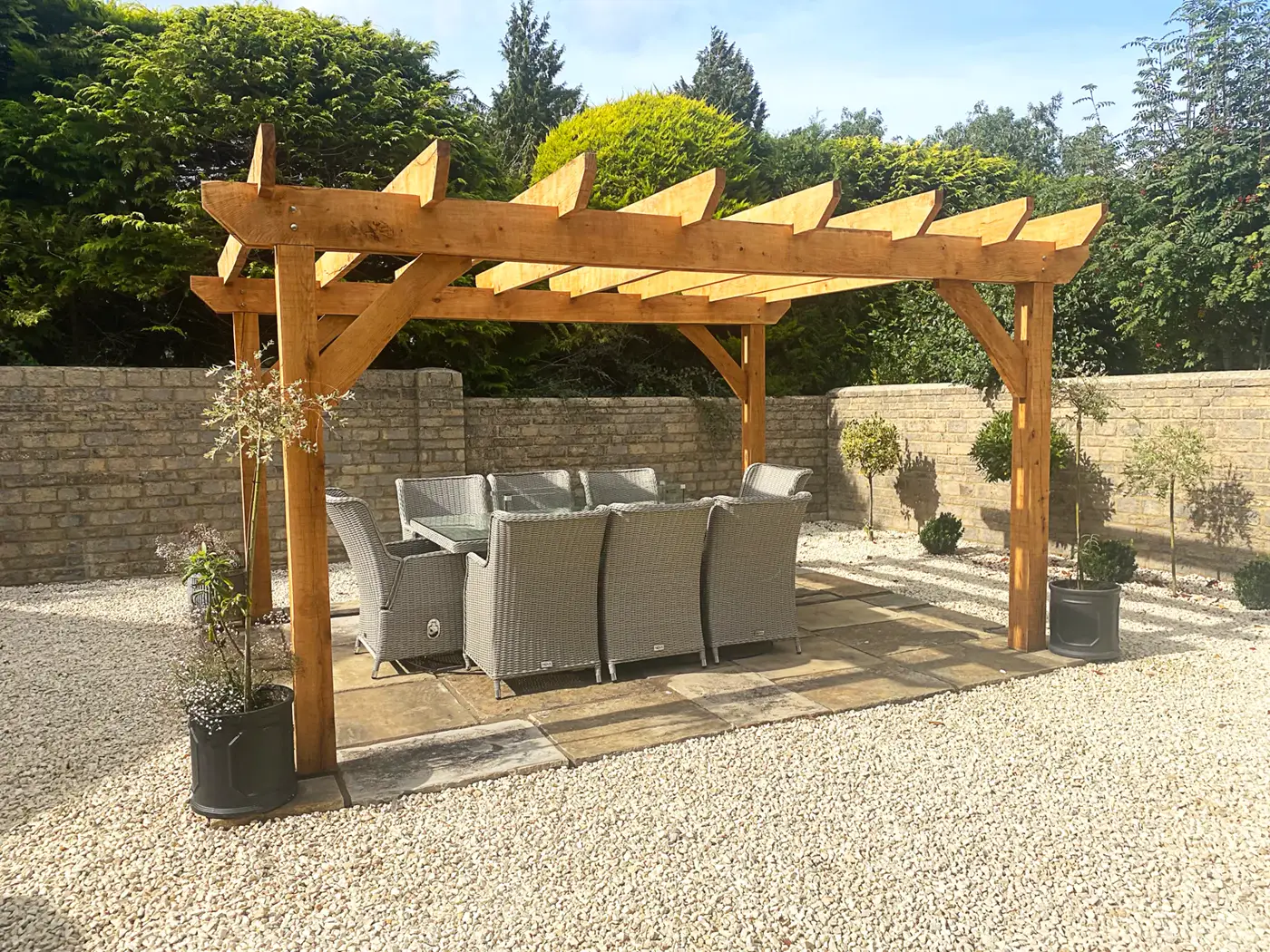 Oak pergola over a gravel terrace with outdoor sofa seating