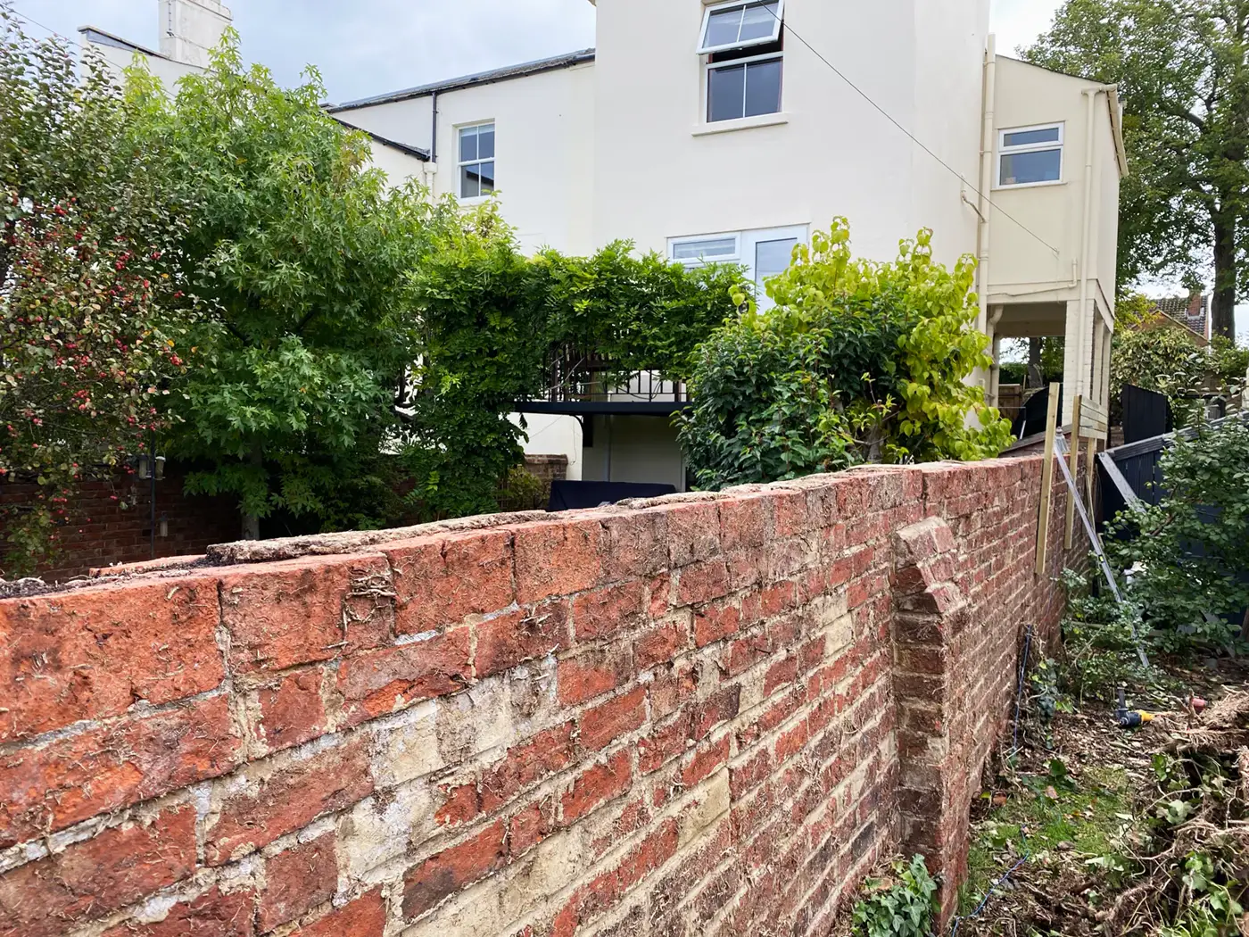 Failing old brick garden wall before rebuilding