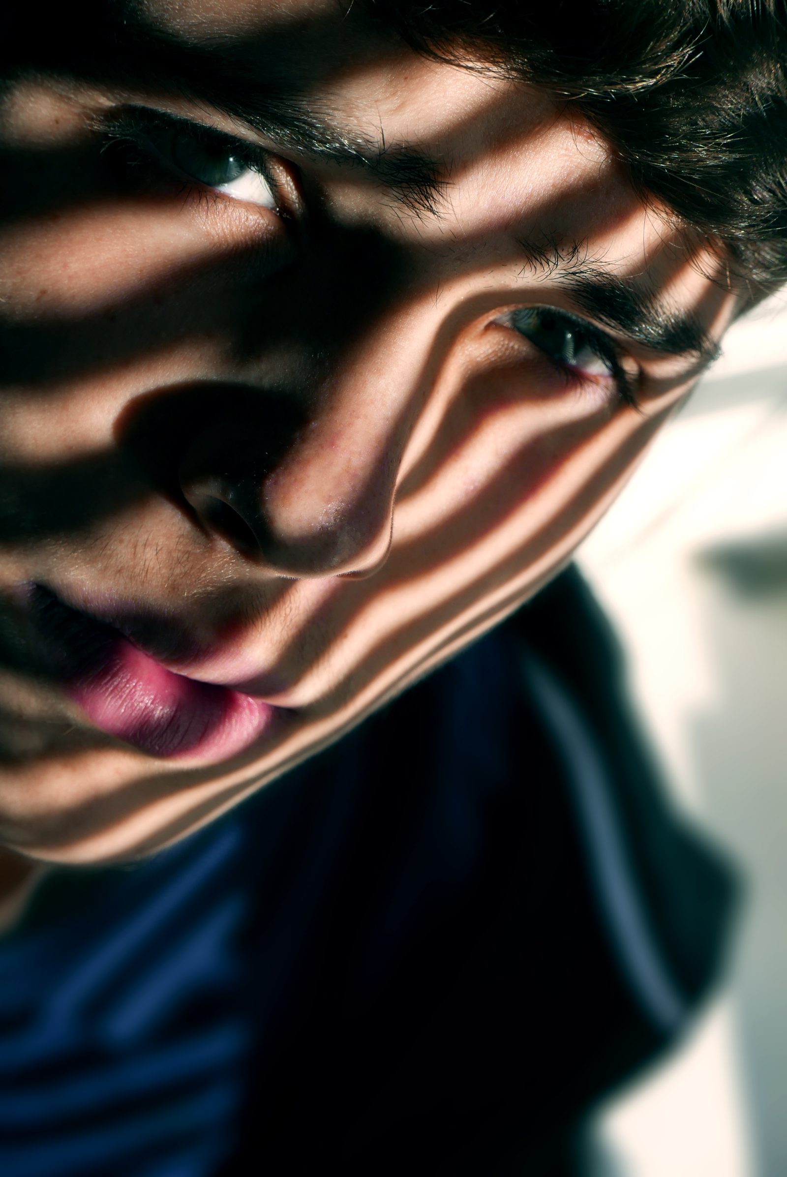 A tight crop of a face behind a hand, shadows and motion blur breaking the features apart