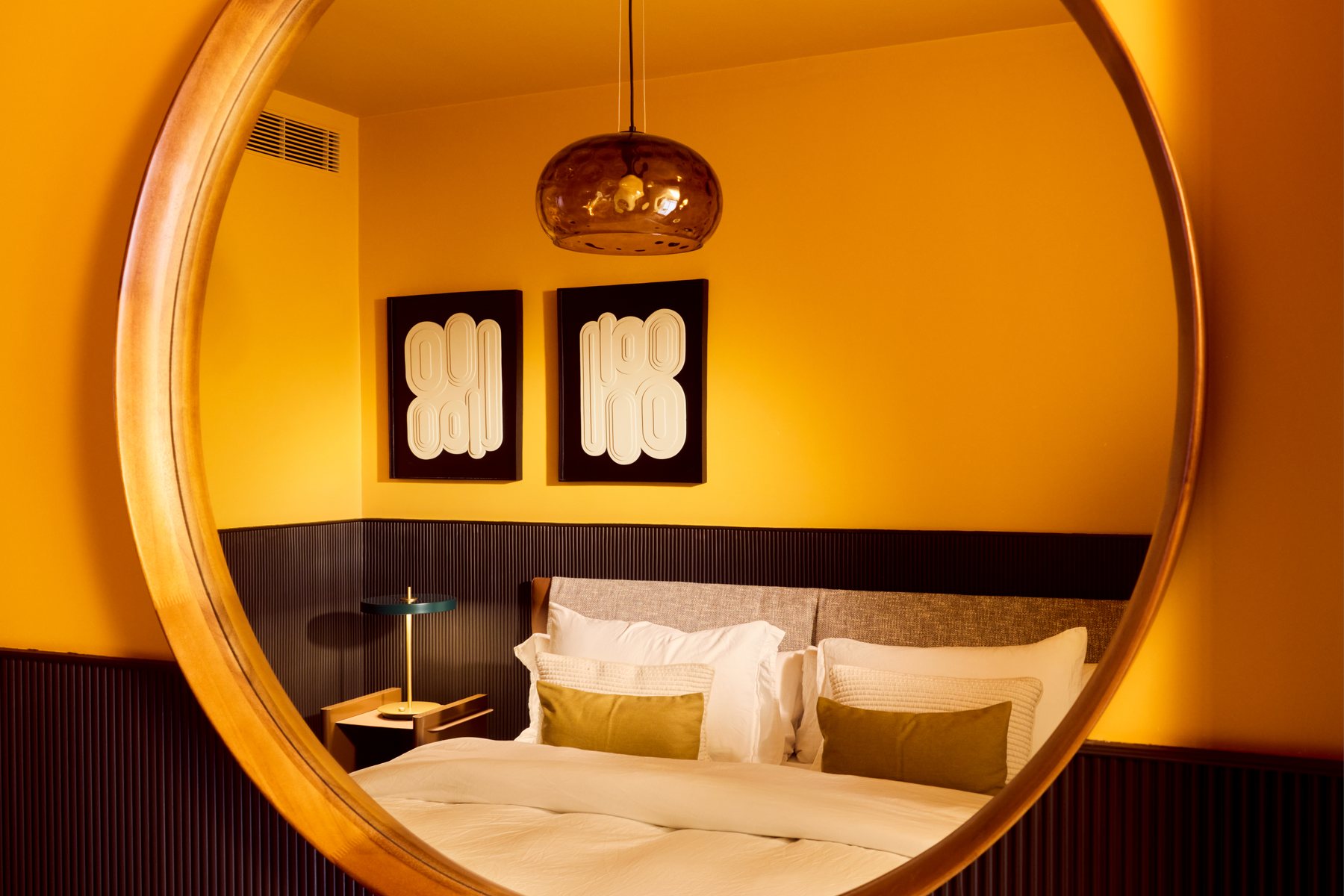 The finished room seen in its round mirror: the two panels on the ochre wall, the fluted panelling and the green lamp